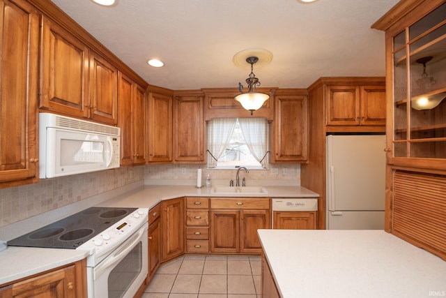 kitchen with sink, tasteful backsplash, decorative light fixtures, light tile patterned floors, and white appliances