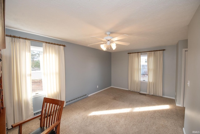 carpeted empty room with baseboard heating, ceiling fan, and a textured ceiling