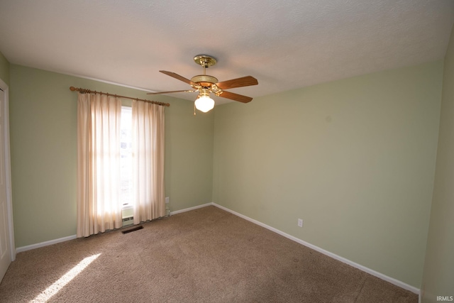 spare room with a textured ceiling, ceiling fan, and carpet