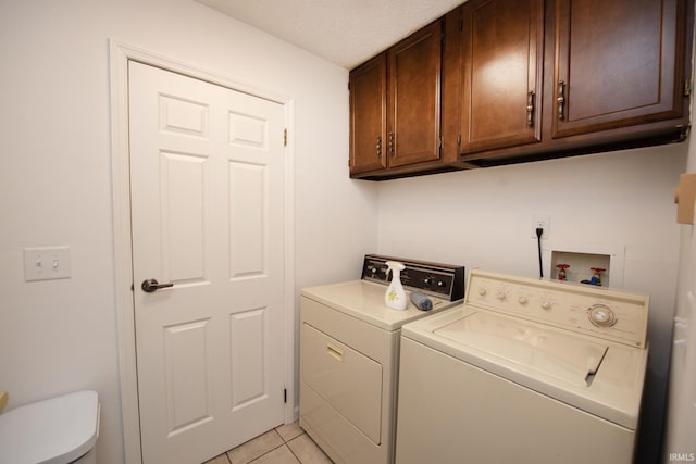 clothes washing area with cabinets, independent washer and dryer, and light tile patterned floors