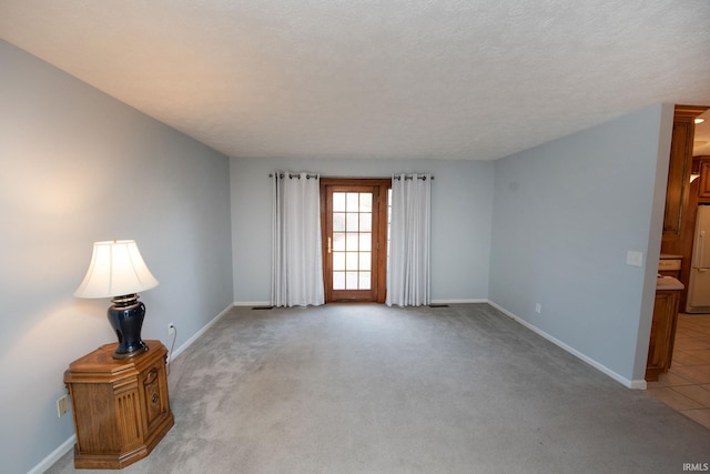 spare room with light carpet and a textured ceiling