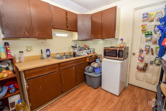 kitchen with fridge, sink, and light hardwood / wood-style flooring