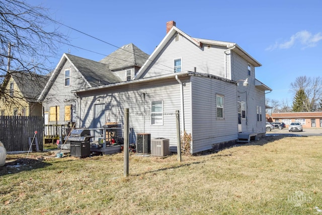 rear view of house with a lawn and central air condition unit