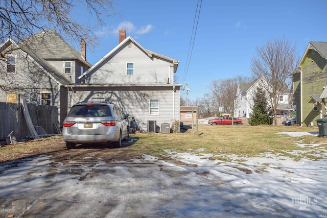 rear view of house featuring cooling unit and a lawn