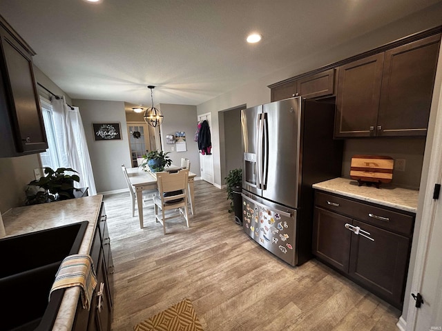 kitchen with pendant lighting, stainless steel fridge, dark brown cabinetry, and light hardwood / wood-style floors