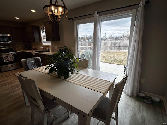 dining space with sink, a chandelier, and light hardwood / wood-style flooring