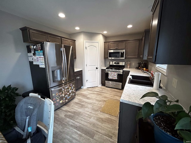 kitchen with dark brown cabinetry, appliances with stainless steel finishes, sink, and light hardwood / wood-style flooring