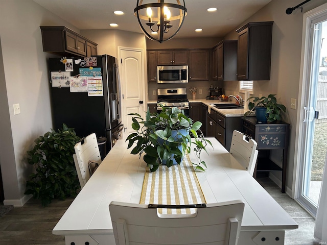 kitchen with hanging light fixtures, dark brown cabinets, sink, and appliances with stainless steel finishes