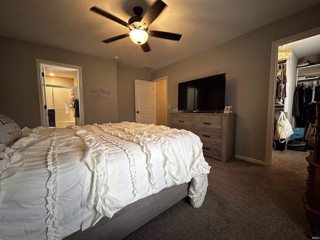 bedroom with ensuite bath, a spacious closet, dark carpet, a closet, and ceiling fan