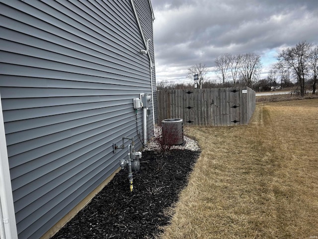 view of property exterior with central AC and a lawn