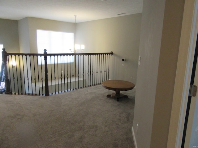 hall with carpet floors and an inviting chandelier