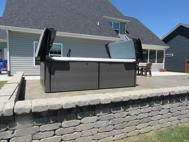 rear view of house featuring a hot tub and a patio area