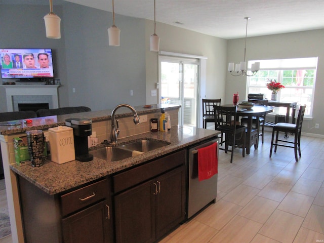 kitchen with sink, light stone counters, decorative light fixtures, dark brown cabinets, and dishwasher