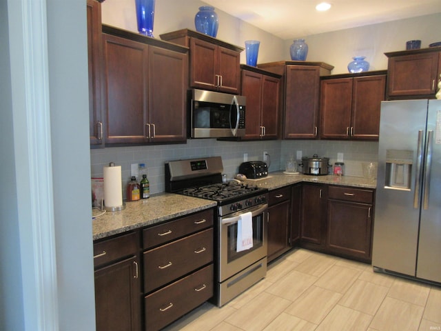 kitchen featuring light stone counters, backsplash, dark brown cabinetry, and appliances with stainless steel finishes