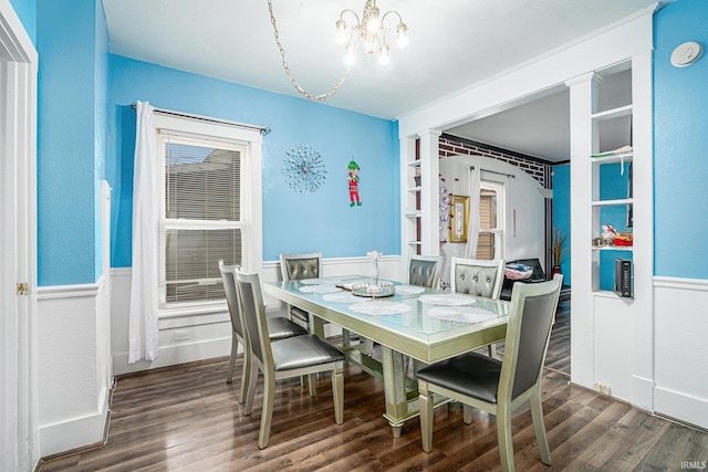 dining area featuring dark wood-type flooring, a chandelier, and ornate columns