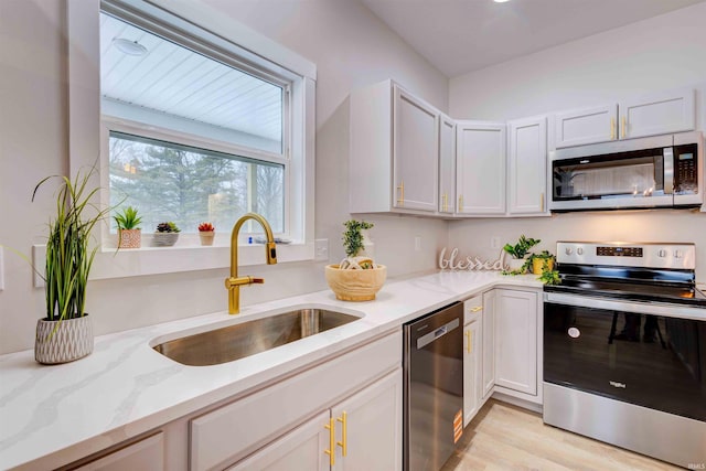 1192 Greer Ln, Springville, IN 47462 - kitchen with appliances with stainless steel finishes, white cabinetry, sink, light stone countertops, and light wood-type flooring
