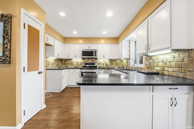 kitchen with white cabinetry, sink, stainless steel appliances, and kitchen peninsula