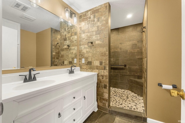 bathroom with tile patterned floors, vanity, and a tile shower