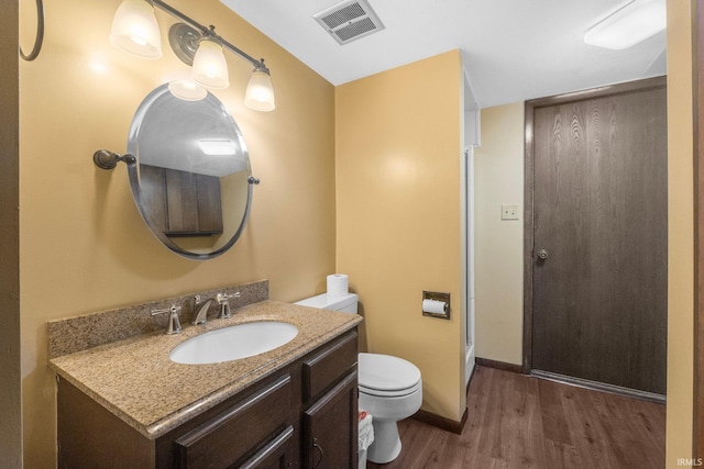 bathroom with vanity, a shower with shower door, hardwood / wood-style floors, and toilet