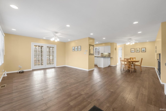 unfurnished living room featuring dark wood-type flooring and ceiling fan