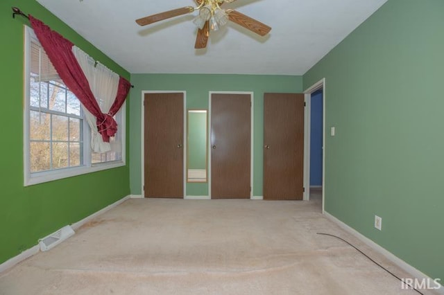 unfurnished bedroom with two closets, carpet floors, and ceiling fan