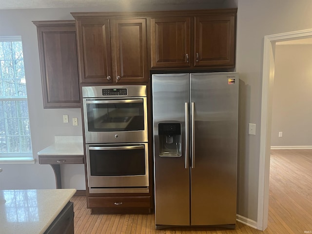 kitchen featuring dark brown cabinetry, light hardwood / wood-style flooring, and stainless steel appliances