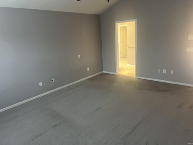 carpeted spare room with vaulted ceiling