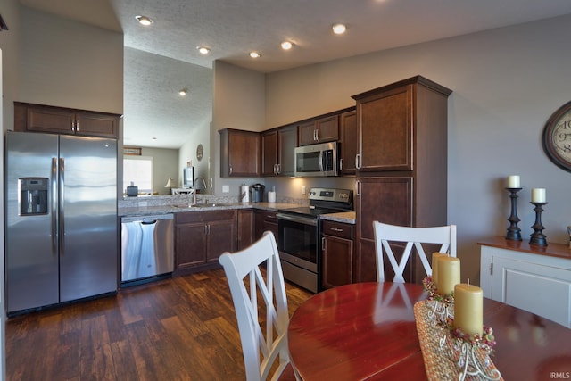 kitchen with lofted ceiling, sink, stainless steel appliances, light stone counters, and dark hardwood / wood-style flooring