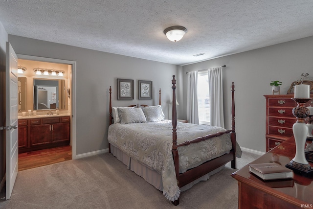 carpeted bedroom with sink, connected bathroom, and a textured ceiling