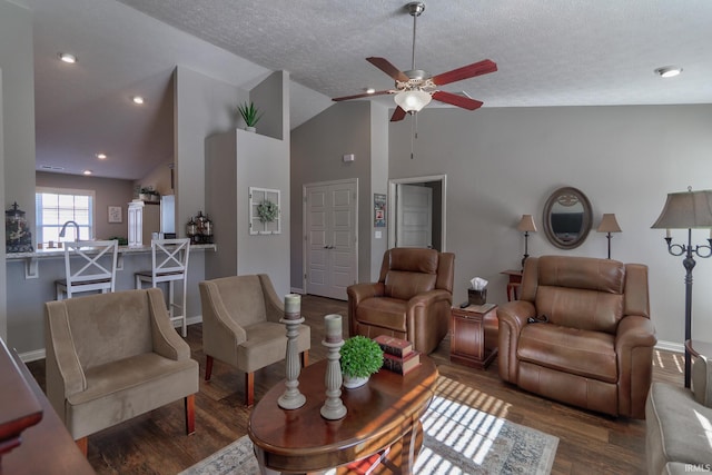 living room featuring dark wood-type flooring, sink, vaulted ceiling, a textured ceiling, and ceiling fan