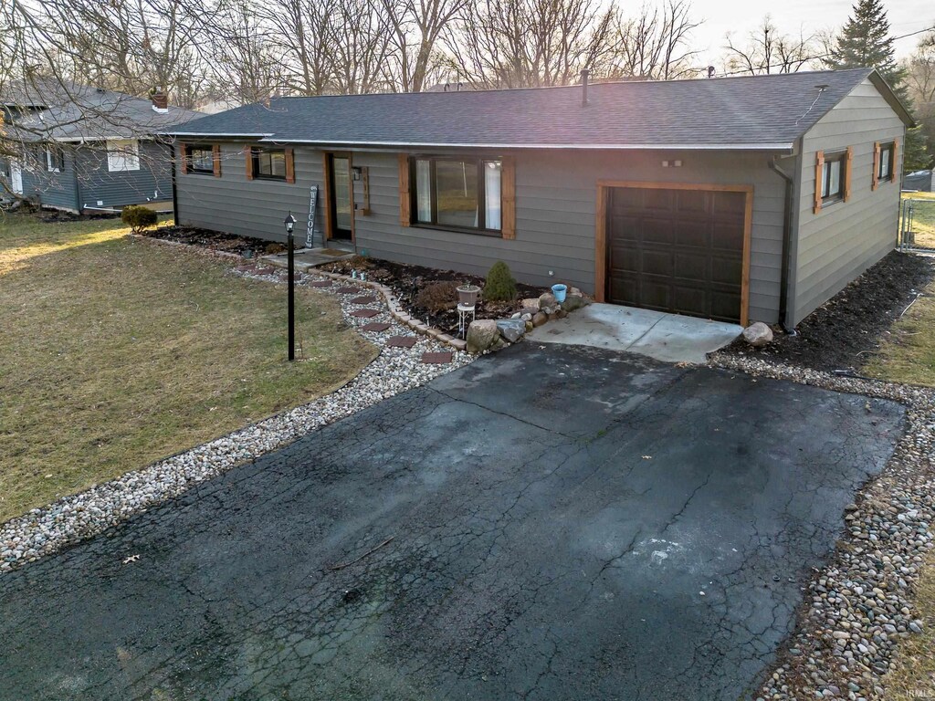 ranch-style home with a garage and a front lawn