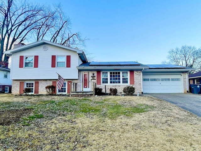 tri-level home featuring a garage and solar panels