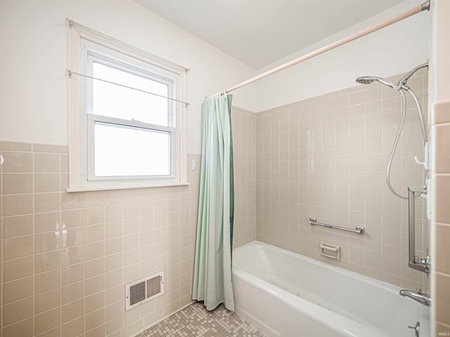 bathroom with tile walls, tile patterned floors, and shower / bathtub combination with curtain