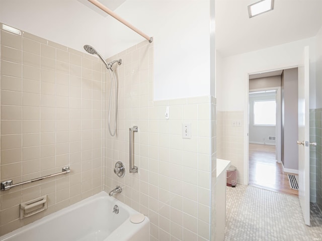 bathroom featuring tile walls, tile patterned flooring, and tiled shower / bath combo