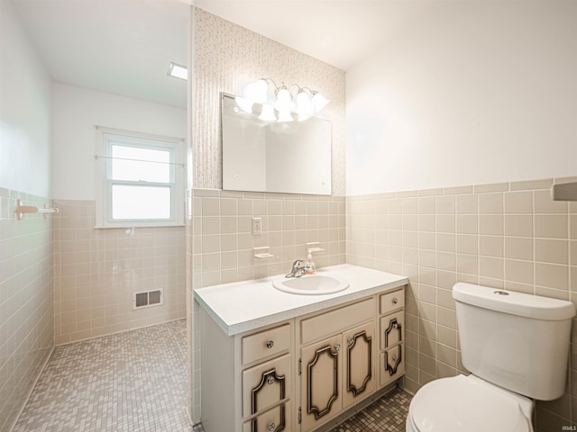 bathroom with tile walls, vanity, tile patterned flooring, and toilet