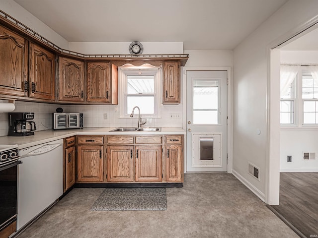 kitchen with white dishwasher, sink, backsplash, and range