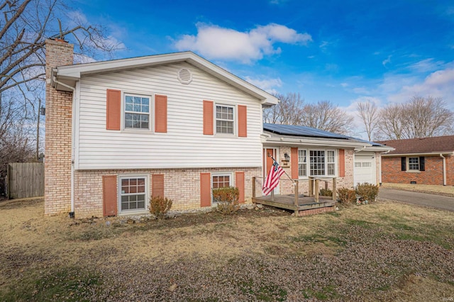 split level home with a front yard and solar panels