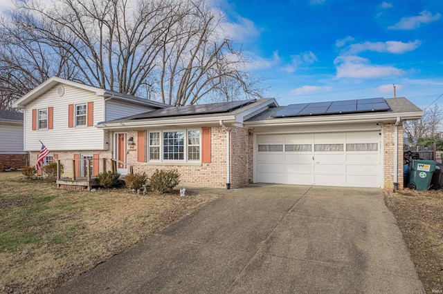 split level home with a garage and solar panels