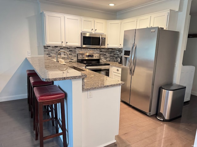 kitchen with stone counters, appliances with stainless steel finishes, kitchen peninsula, and white cabinets