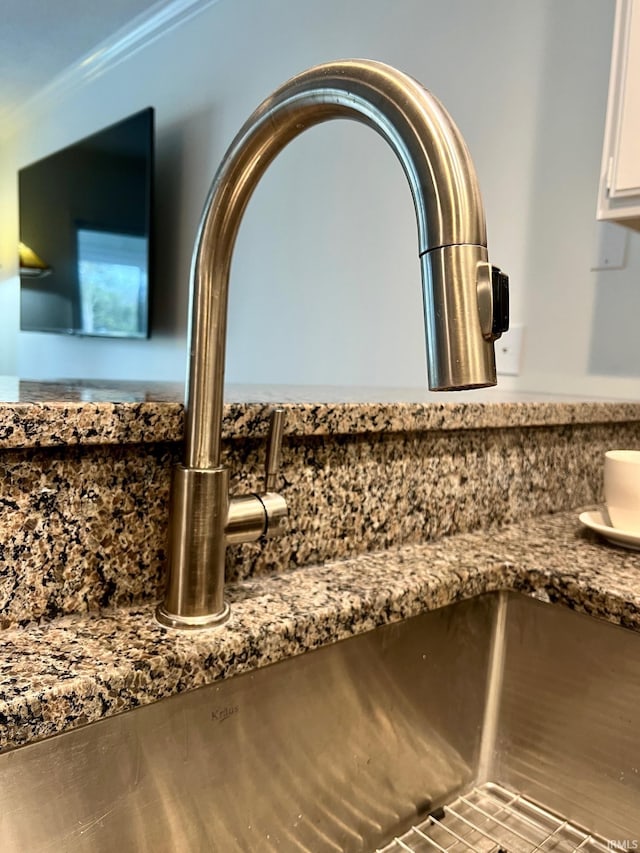 interior details with white cabinetry, stone countertops, and sink