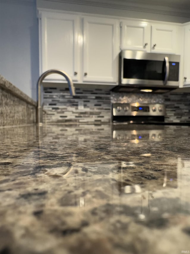 kitchen with tasteful backsplash, white cabinets, and appliances with stainless steel finishes