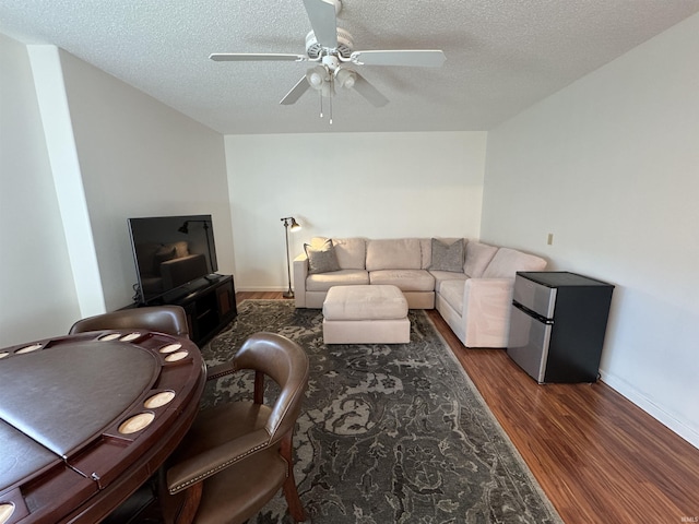 living room featuring ceiling fan, dark hardwood / wood-style floors, and a textured ceiling