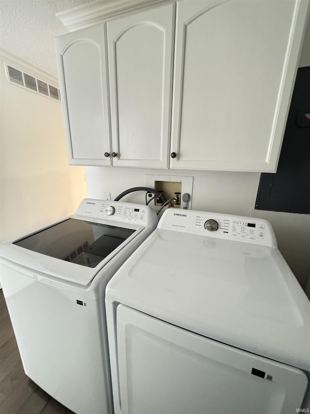 washroom with cabinets, washing machine and clothes dryer, dark wood-type flooring, and a textured ceiling