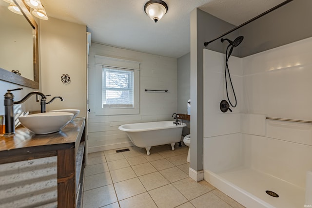 bathroom featuring tile patterned flooring, vanity, walk in shower, toilet, and a textured ceiling