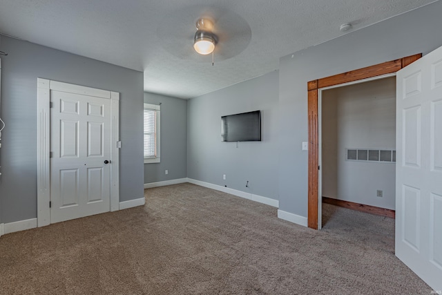 unfurnished bedroom featuring ceiling fan, carpet flooring, and a textured ceiling