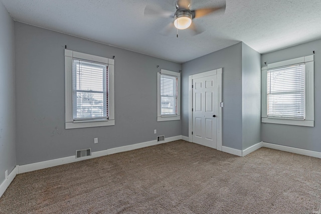 unfurnished bedroom featuring ceiling fan, light colored carpet, a textured ceiling, and a closet