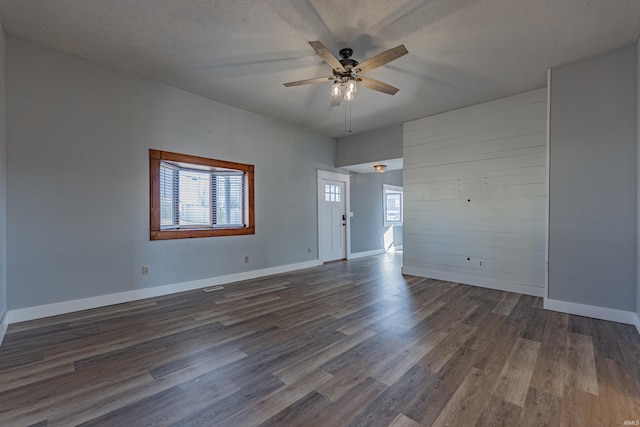 empty room with dark wood-type flooring, ceiling fan, and a textured ceiling