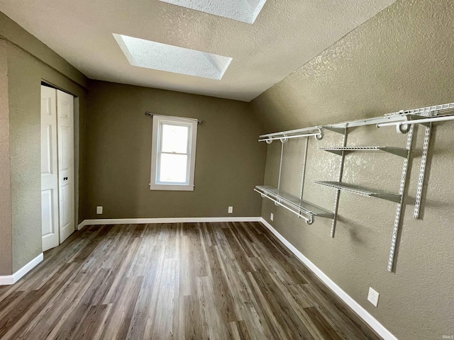 spacious closet featuring dark hardwood / wood-style flooring and lofted ceiling with skylight