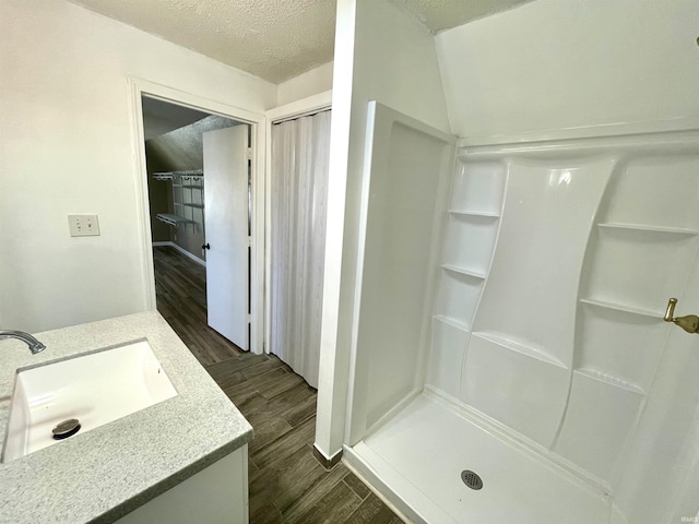 bathroom with hardwood / wood-style flooring, vanity, a textured ceiling, and walk in shower