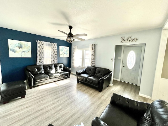 living room featuring a textured ceiling, ceiling fan, and light wood-type flooring